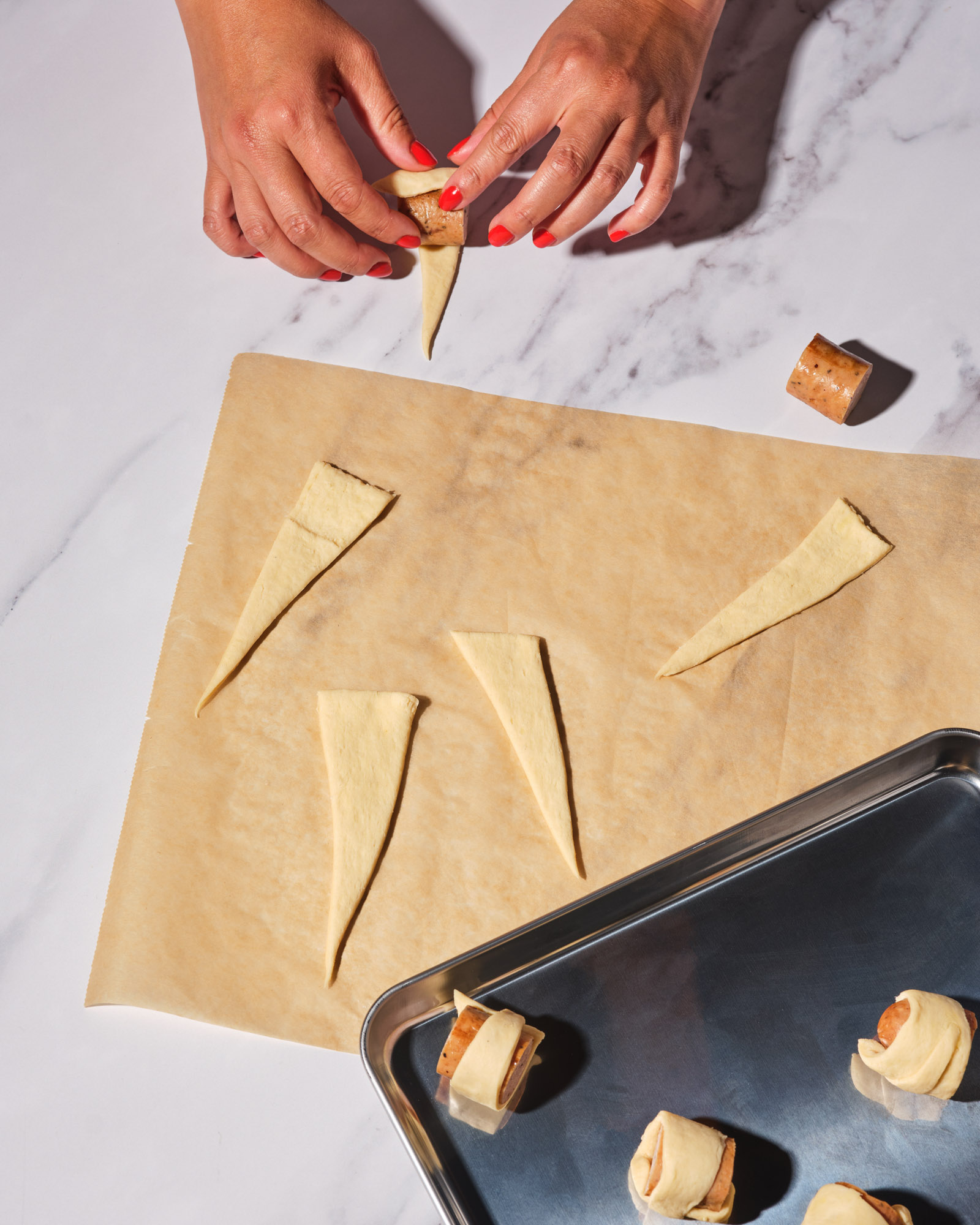 Unbaked bite-size crescent-wrapped chicken sausages served with maple-Dijon dipping sauce on a platter.