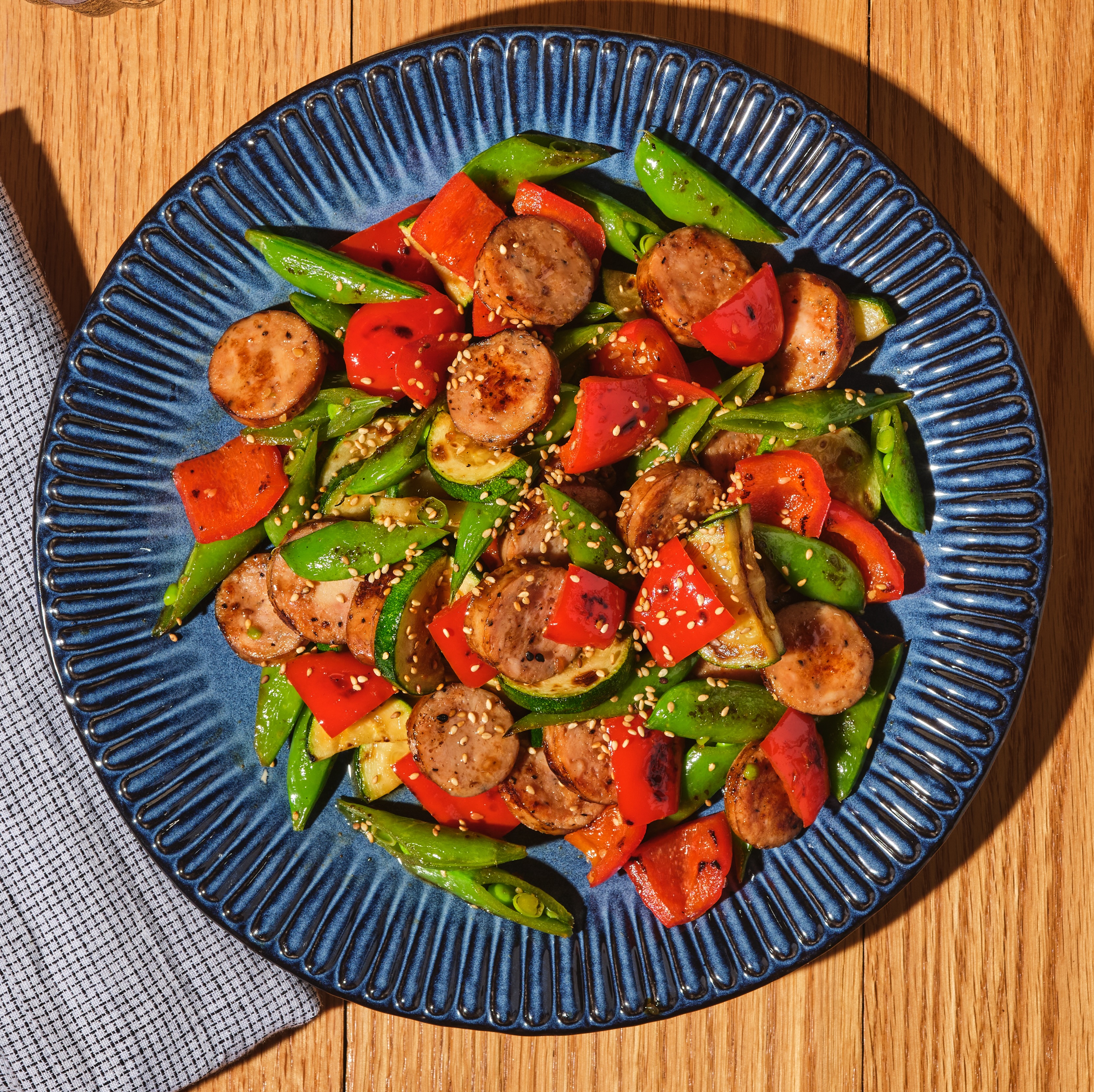 Colorful chicken sausage teriyaki stir-fry with bell peppers, zucchini, and snow peas served over steamed rice.