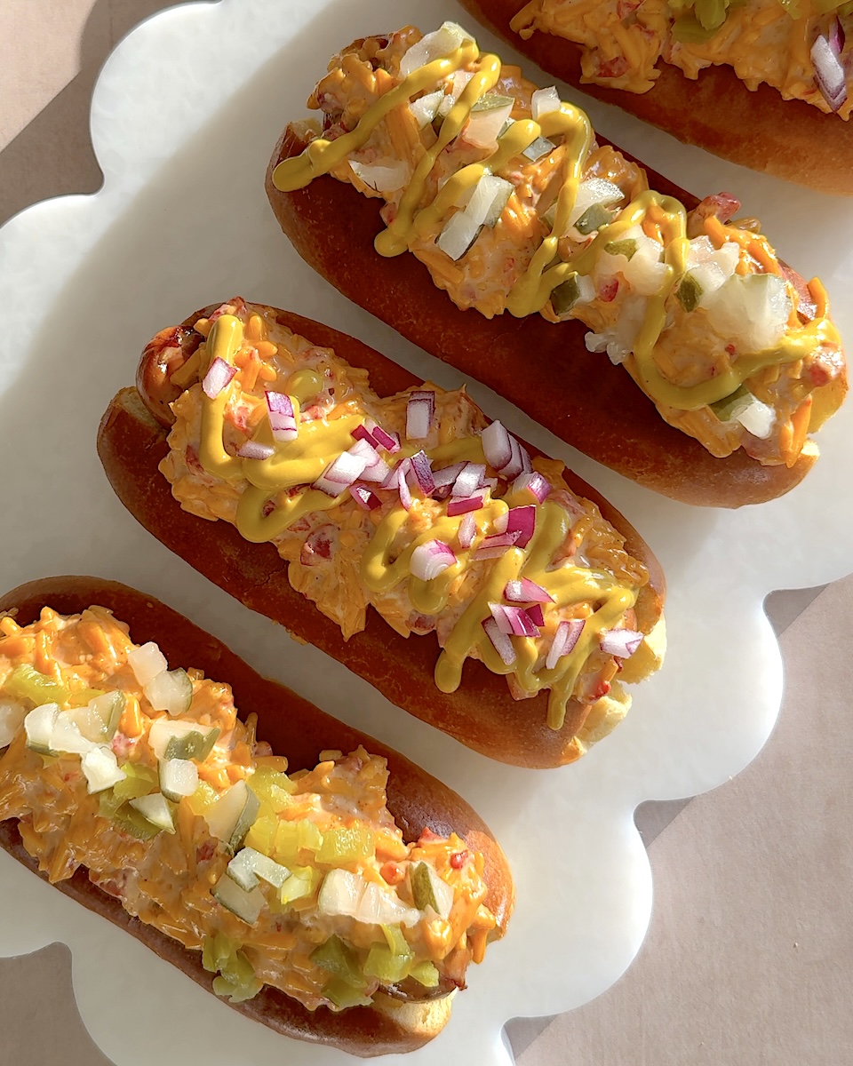 A platter of pimento cheese dogs made with The Sausage Project Melty Cheddar.