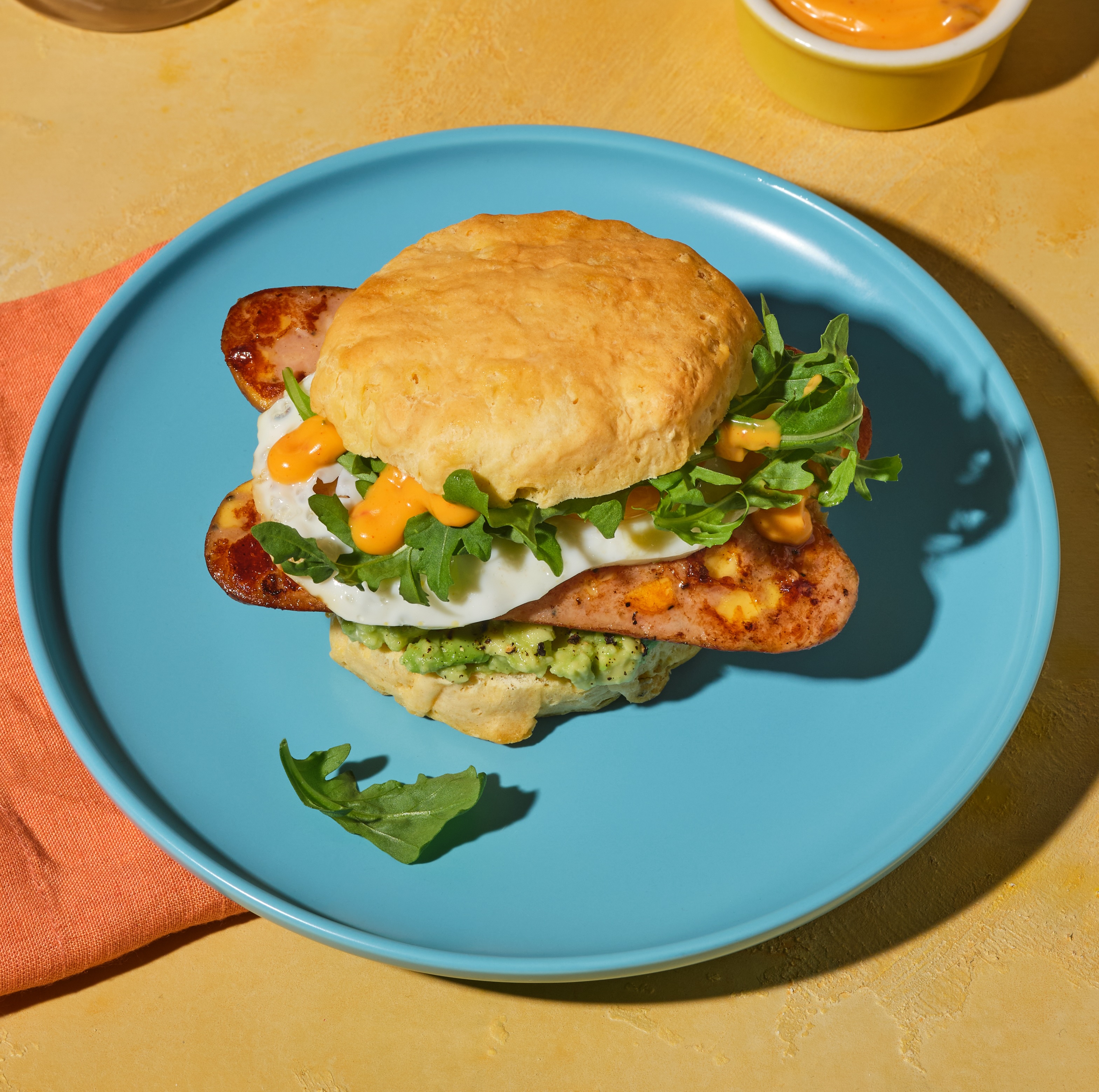 Flaky biscuit sandwich stuffed with melty cheddar chicken sausage, fried egg, avocado, arugula, and chipotle mayo.
