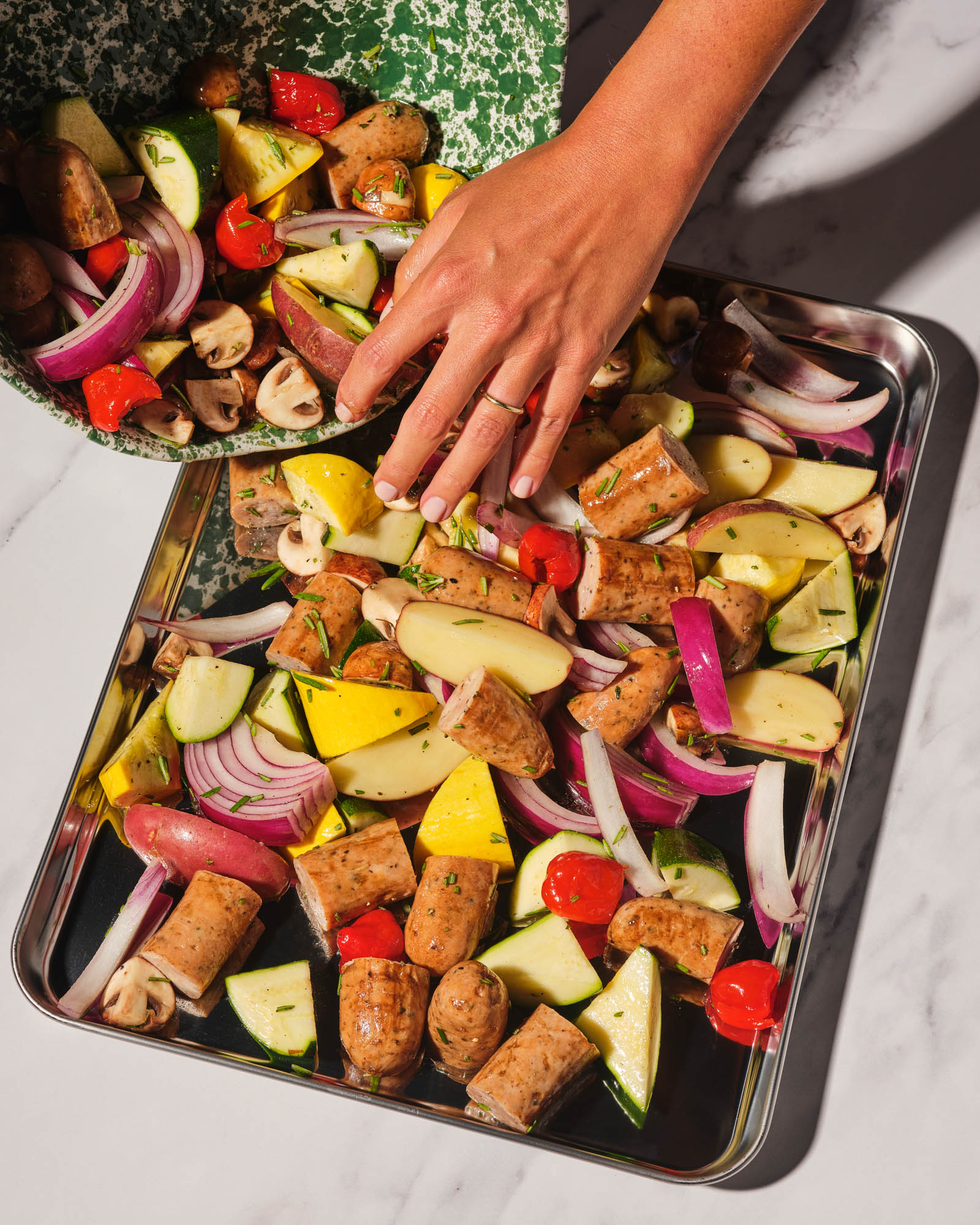 Sheet pan of roasted Italian Herb chicken sausage with colorful vegetables, rosemary, and olive oil.