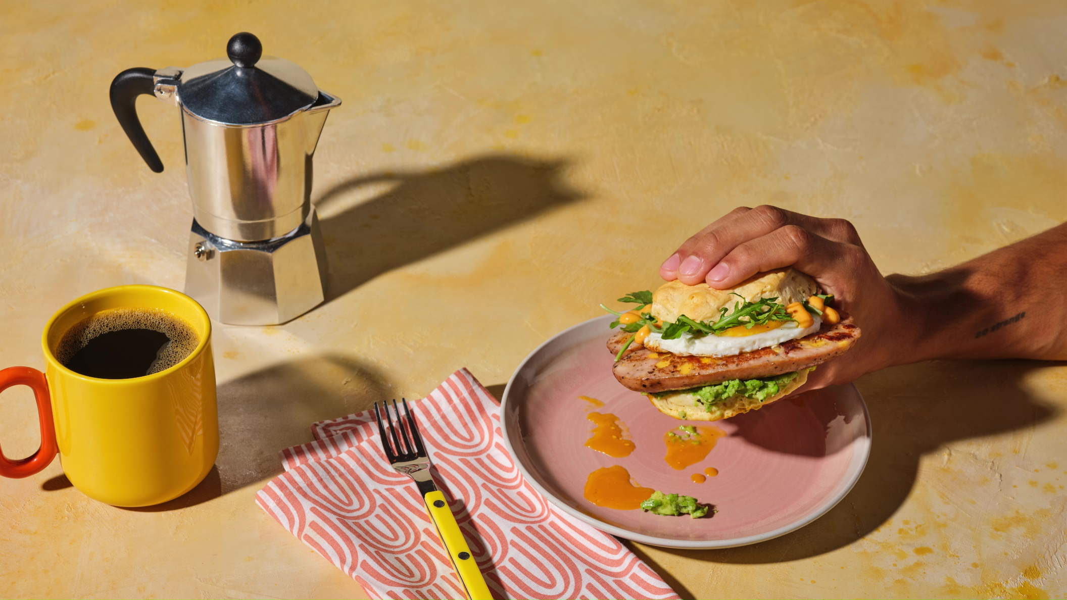 A delicious biscuit and Melty Cheddar Chicken Sausage breakfast sandwich served with a fresh mug of coffee.