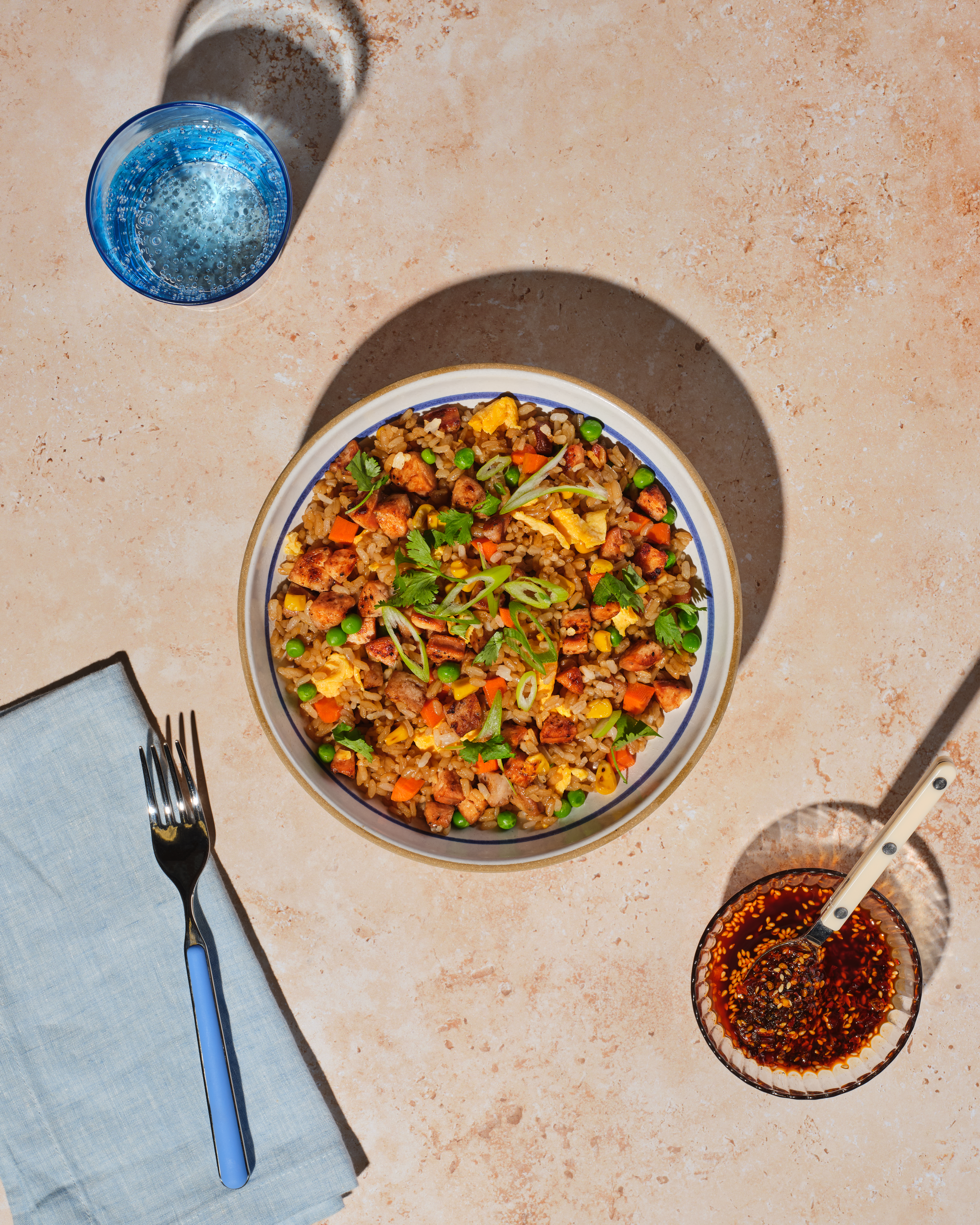 A bowl of golden fried rice with Classic Roasted Chicken Sausage coins, colorful vegetables, and savory sauce.