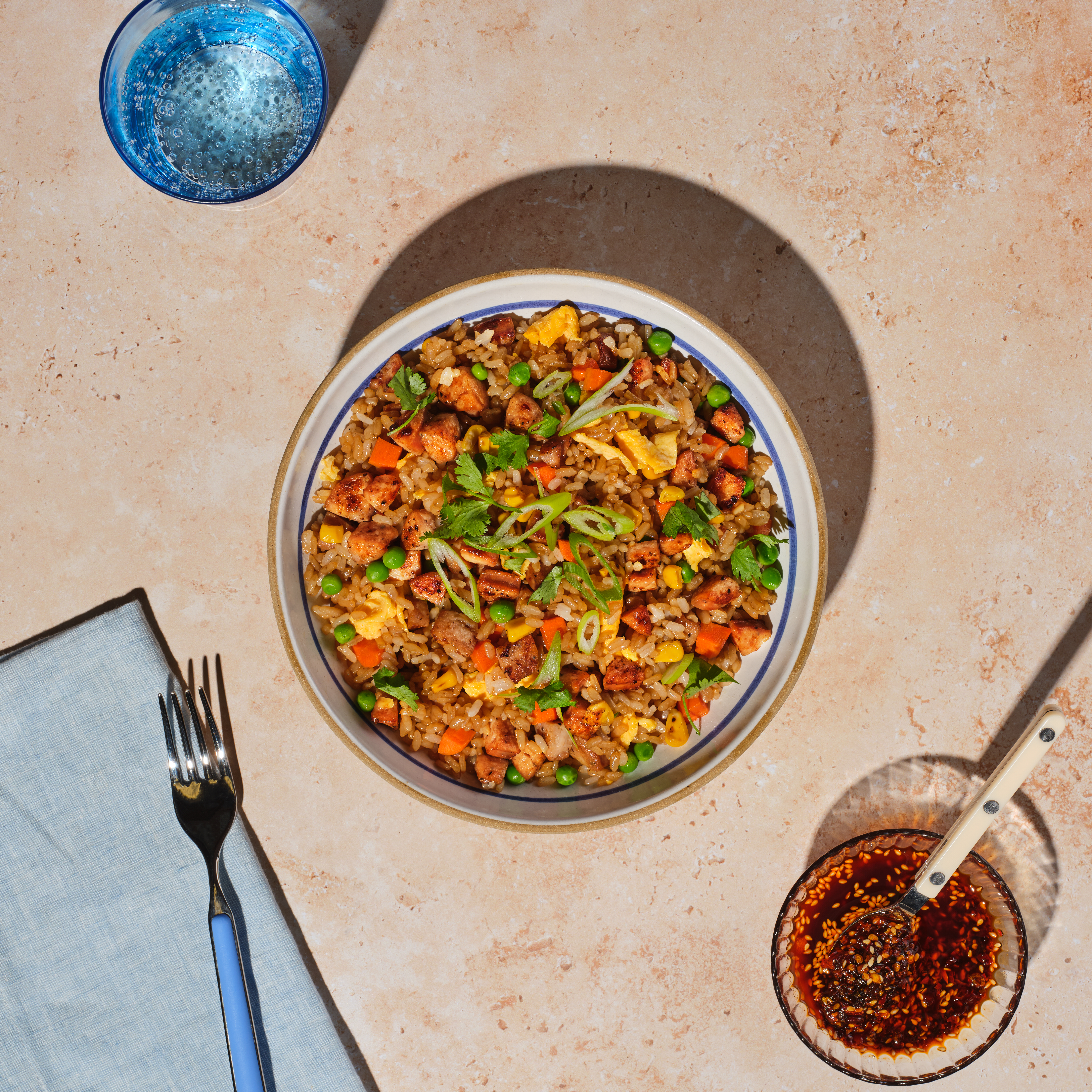 A colorful bowl of fried rice made with The Sausage Project's chicken sausage and served with a side of sesame sauce.