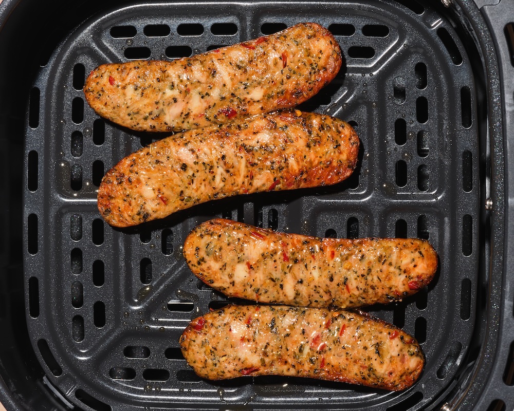 Butterflied The Sausage Project Italian Herb Chicken Sausages cooking in an air fryer.