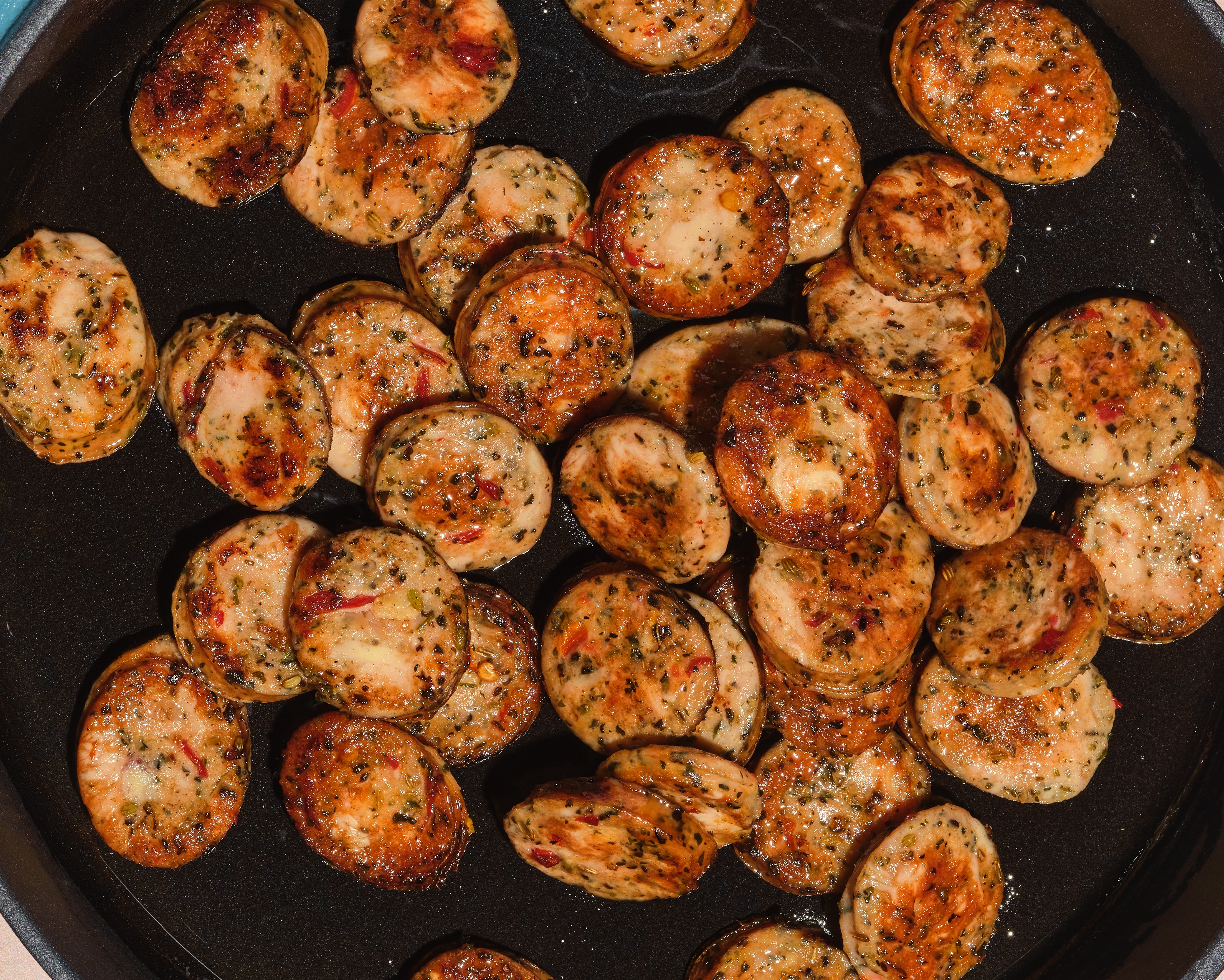 The Sausage Project Italian Herb Chicken Sausage sliced into coins and gently sauteeing in a pan.