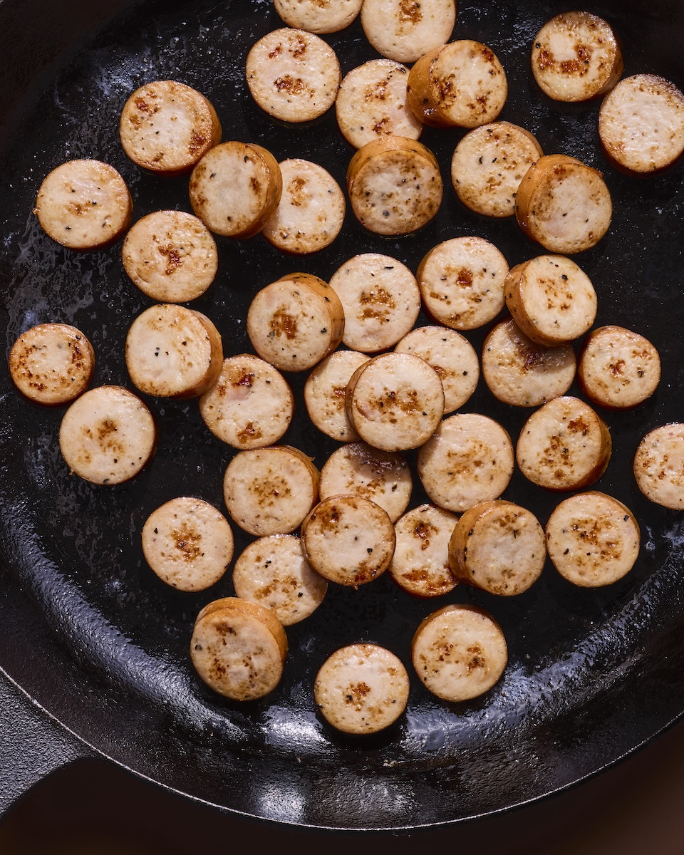 The Sausage Project Classic Roasted Chicken Sausages cut into coins and cooking in a skillet.