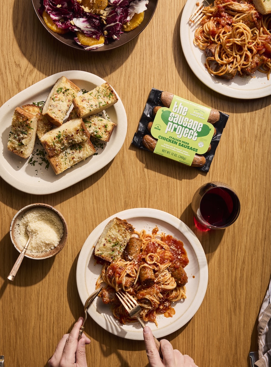 Hands grabbing at a delicious spaghetti dinner.