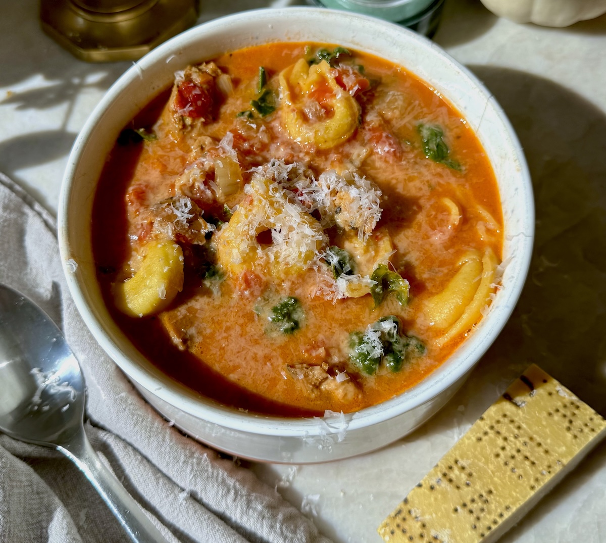 A creamy bowl of tortellini soup with chicken sausage.