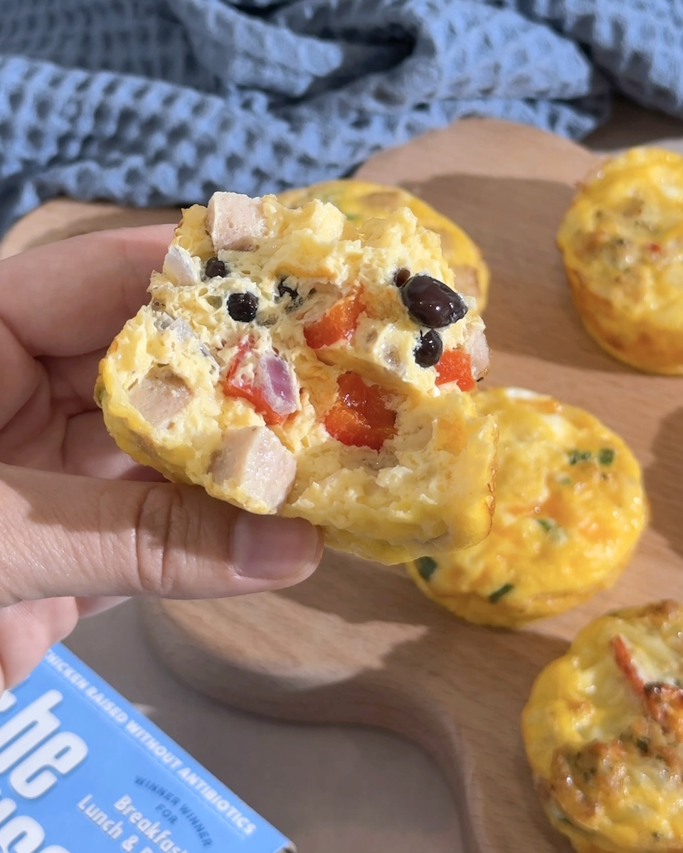 An egg bite pulled apart to reveal tomatoes, olives, and The Sausage Project chicken sausage.