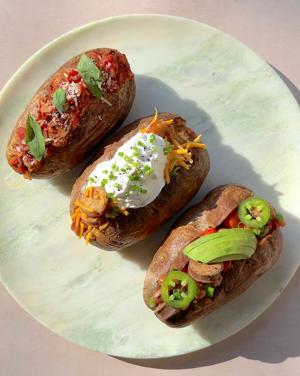 A trio of baked potatoes topped with The Sausage Project chicken sausage.