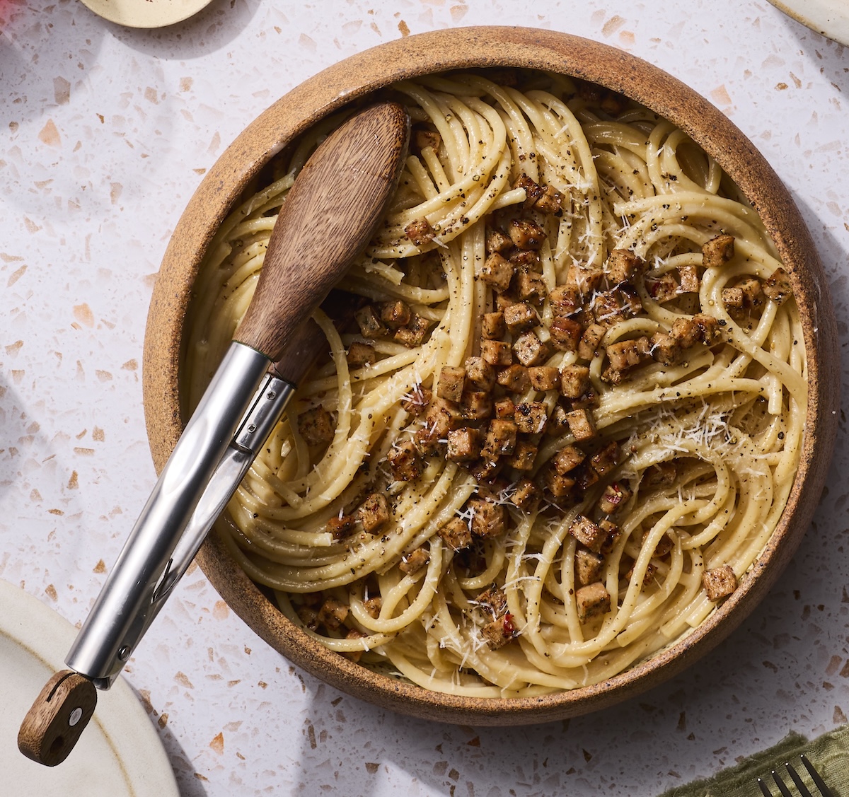 A bowl of bucatini cacio e pepe topped with The Sausage Project Italian Herb Chicken Sausage.