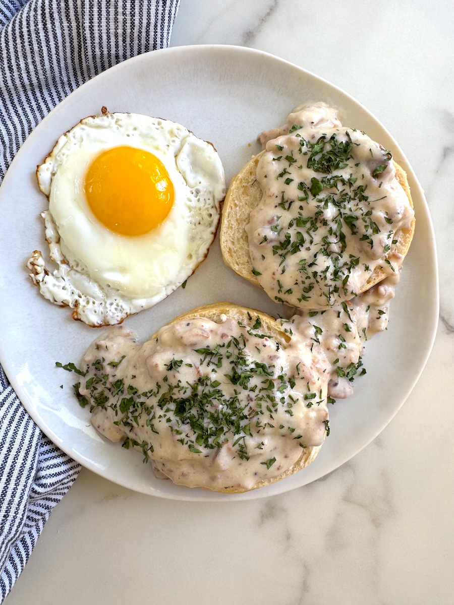A plate of chicken sausage biscuits and gravy with fried egg.
