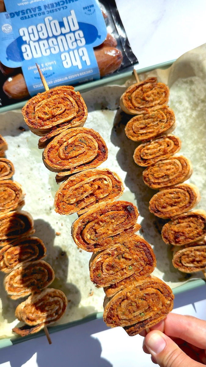 A baking tray full of spiral Chicken Sausage kabob pinwheels.
