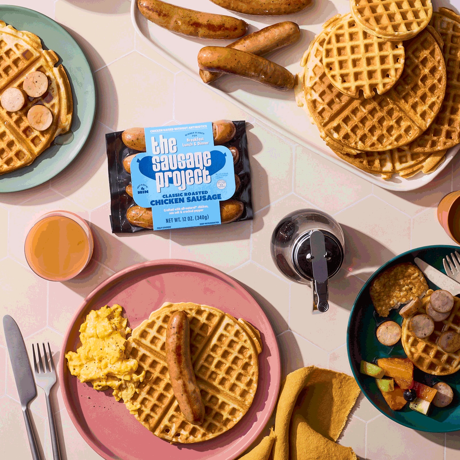 A brunch spread featuring chicken sausage and waffles bring smothered in syrup.