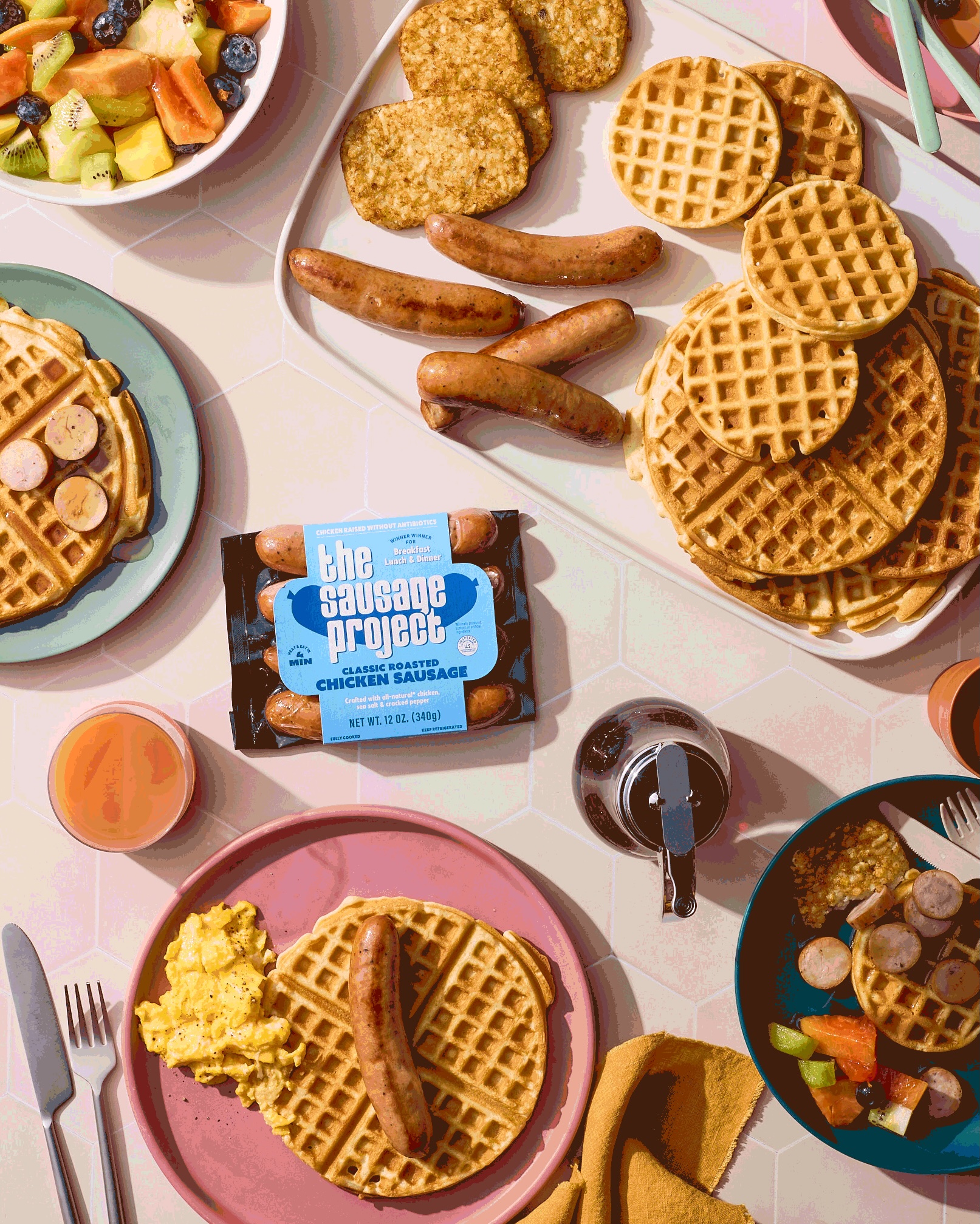 A brunch spread featuring chicken sausage and waffles bring smothered in syrup.