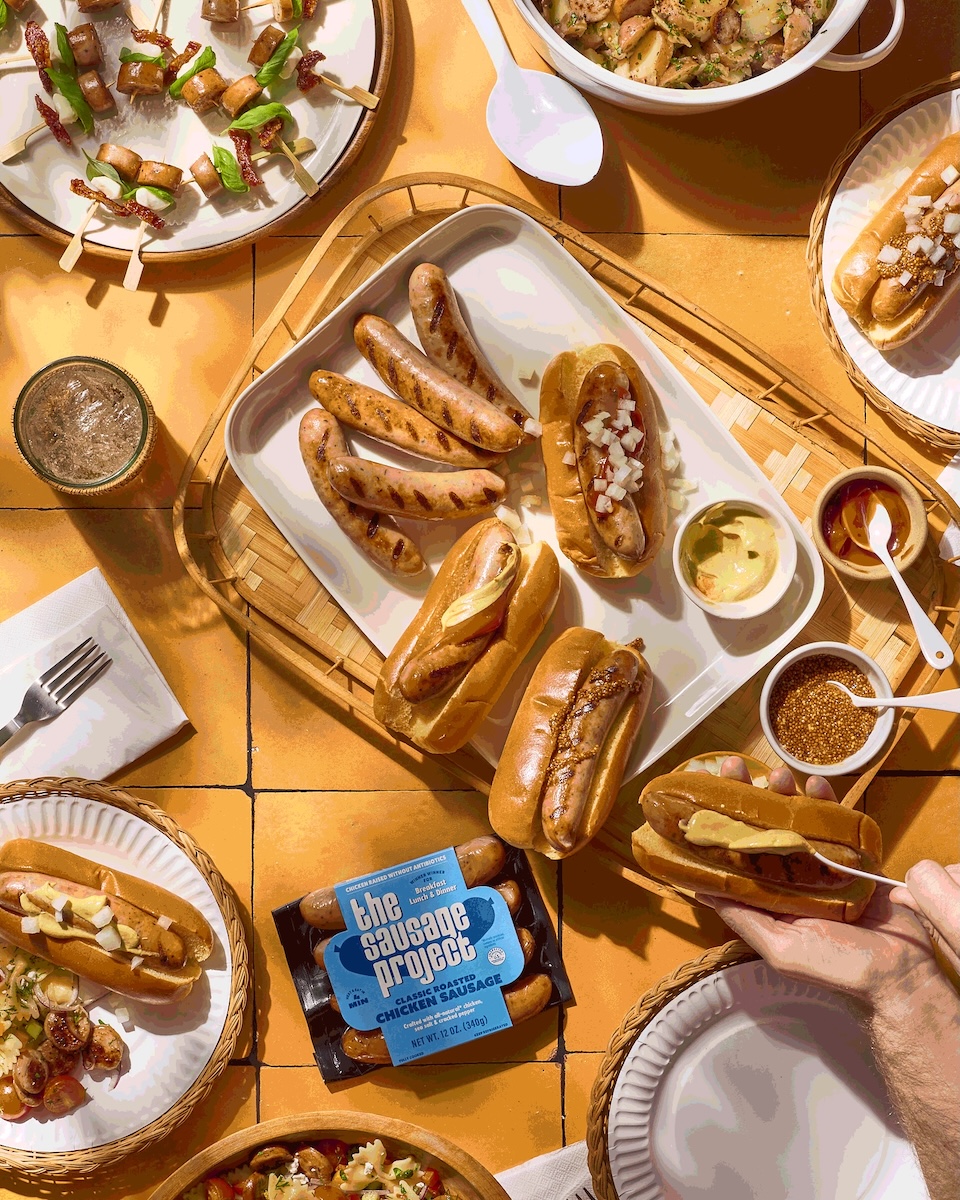 A table full of delicious grill sides and sausafes.