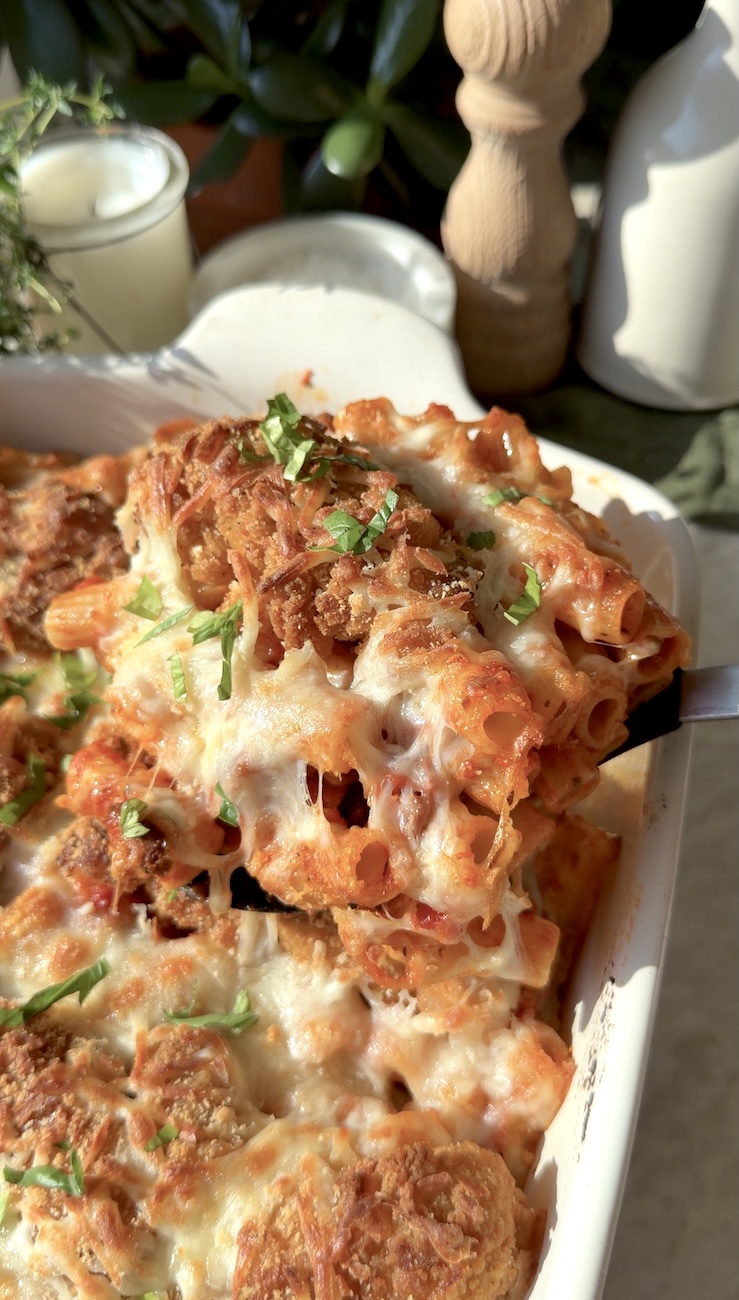 A hand serving cheesy Chicken Parm Pasta bake.