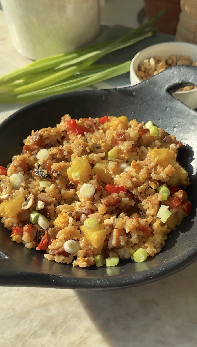 A bowl of pineapple fried rice with chicken sausage.